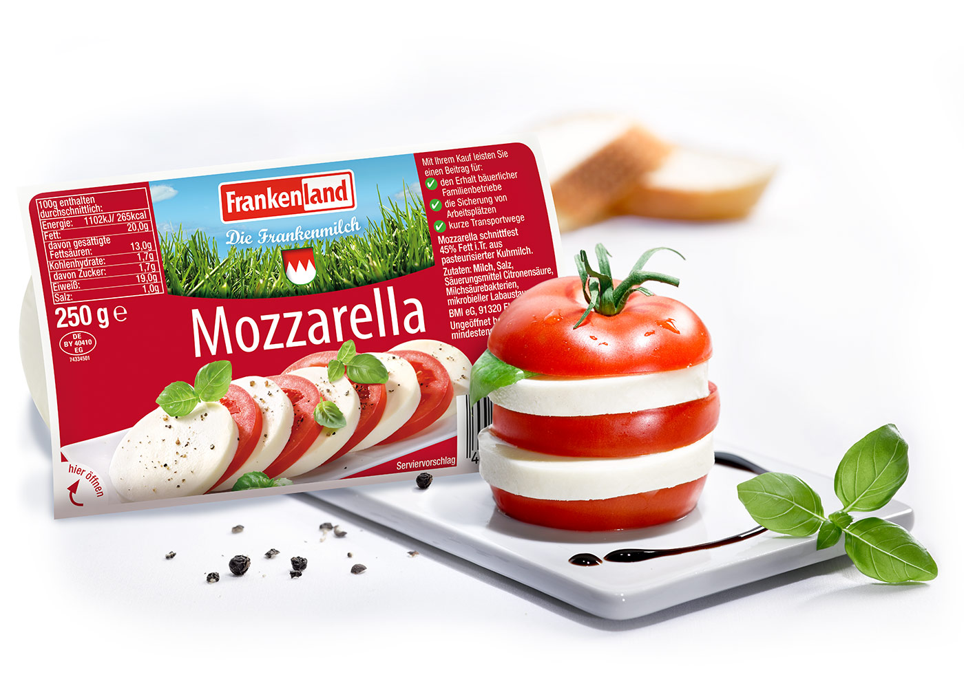 Packung Frankenland Mozzarella neben einem Tomate-Mozzarella-Türmchen mit Basilikum