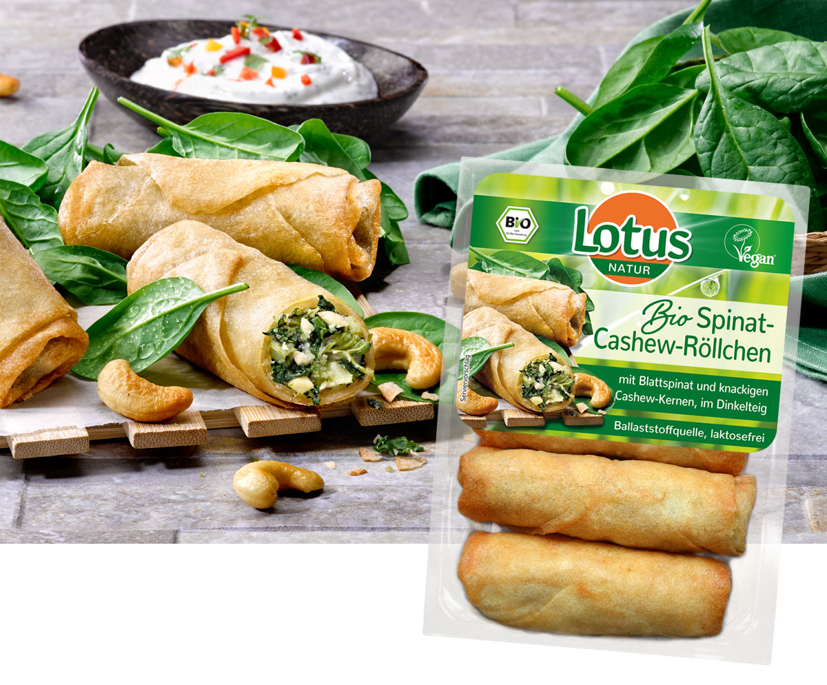 Packung Lotus Bio Spinat-Cashew-Röllchen neben aufgeschnittenen Röllchen mit Blattspinat
