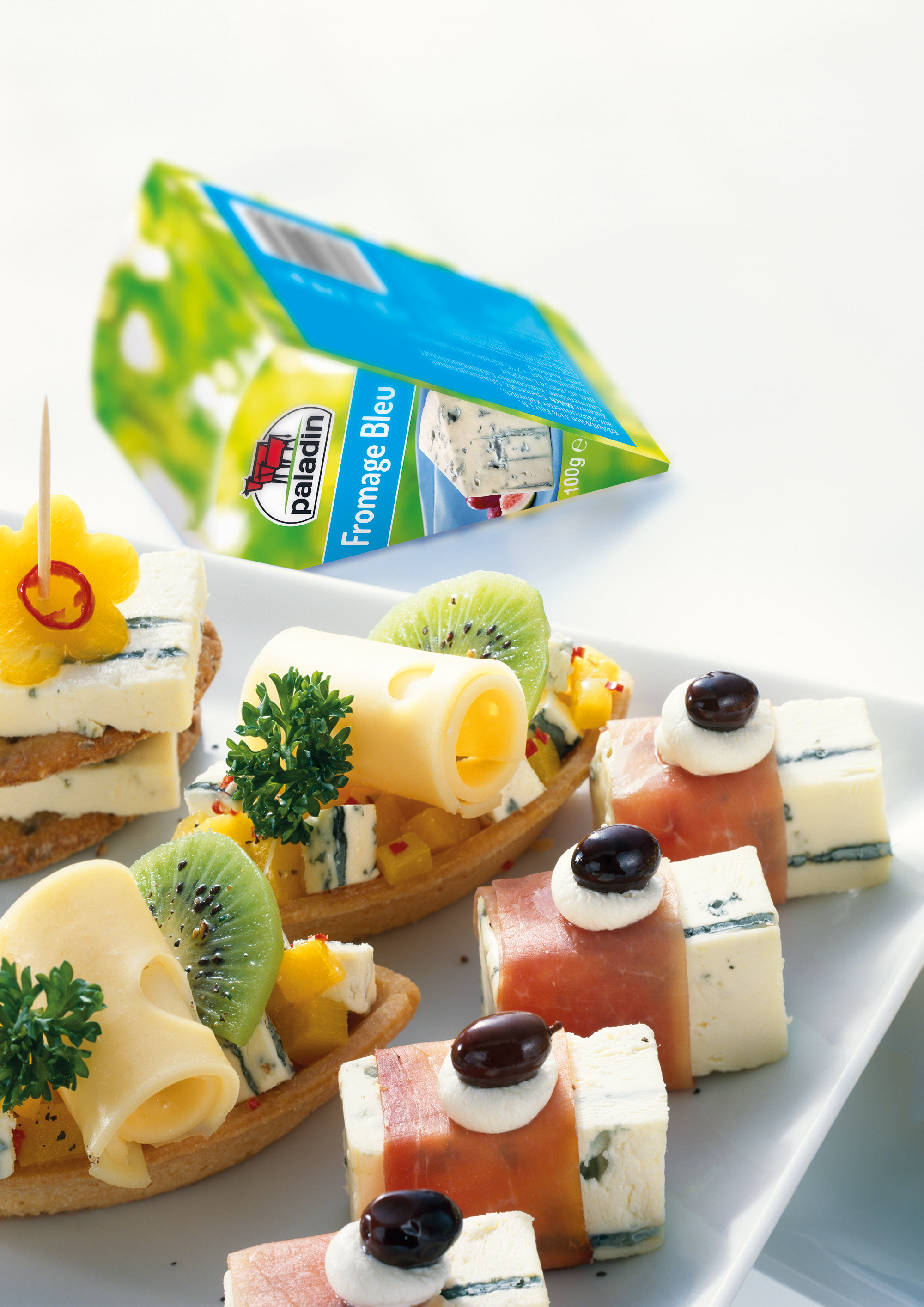 Packung Paladin Fromage Bleu hinter belegten Canapés mit Blauschimmelkäse und Obst