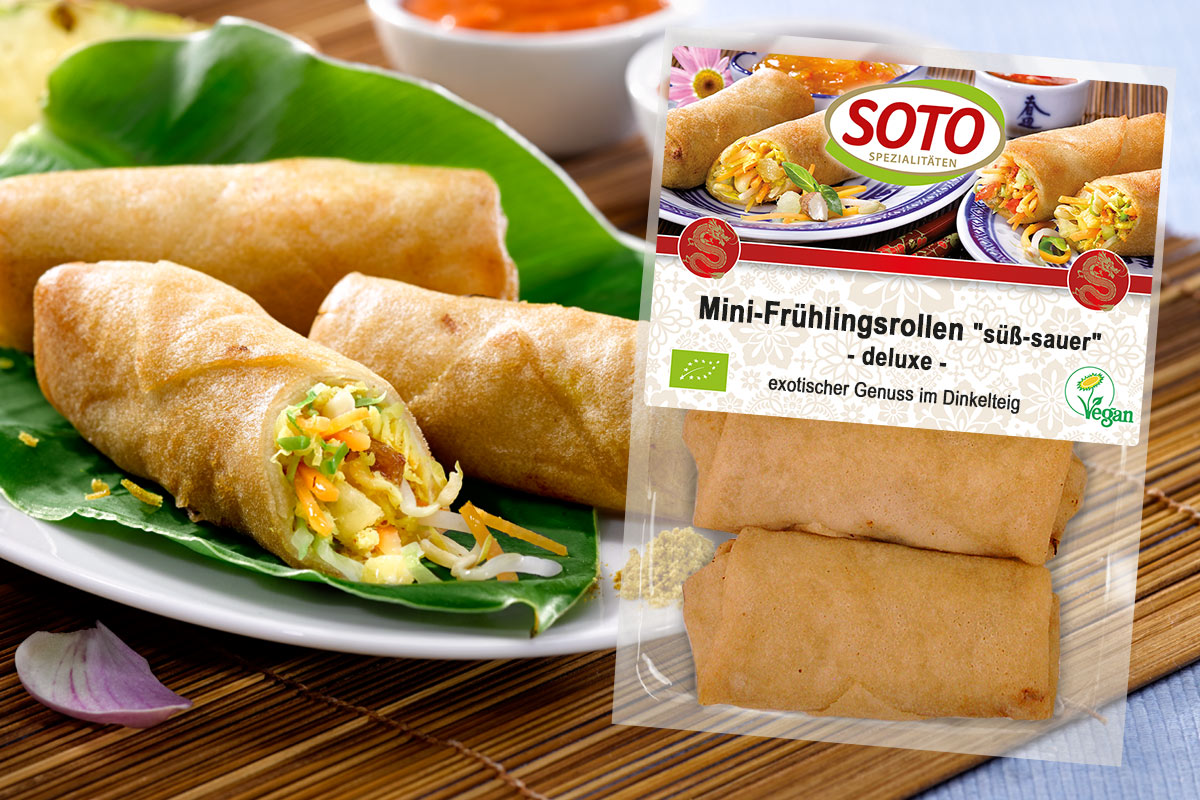 Packung SOTO Mini-Frühlingsrollen süß-sauer neben gefüllten Rollen auf einem Bananenblatt